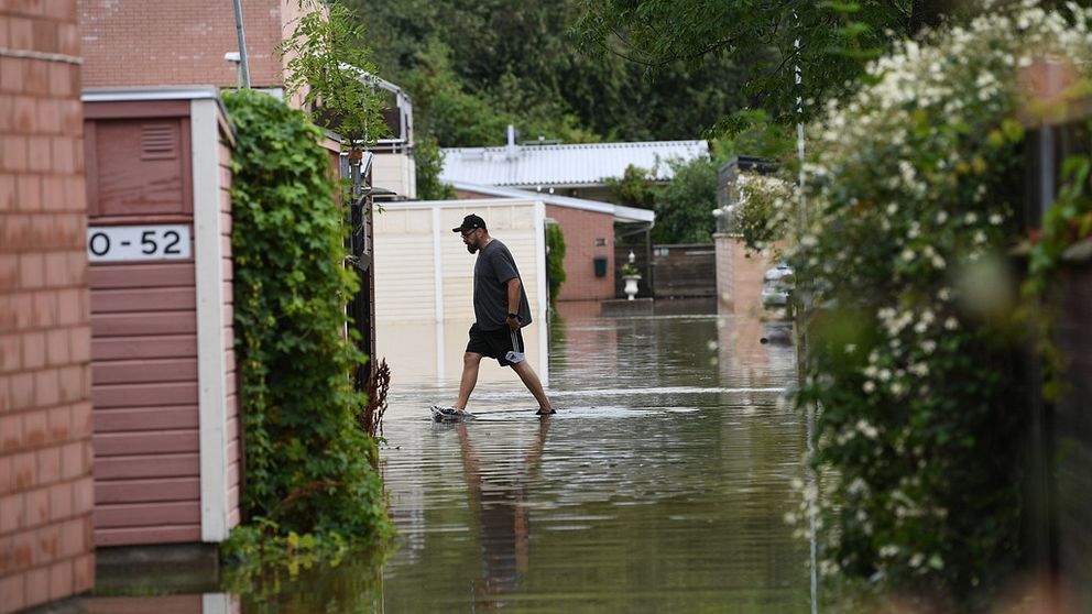 Man som går genom vatten i ett bostadsområde