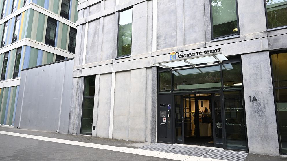 Entrén till en modern byggnad som tillhör ”Chalmers Tekniska Högskola”. Fasaden är i betong med stora fönster och ett klart överhäng vid ingången, som är markerad med en glasdörr. Byggnaden ligger i ett område med flera moderna byggnader i olika färger.