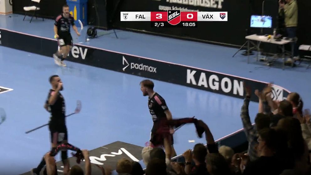 Innebandyspelare firar mål på planen medan publik jublar.
