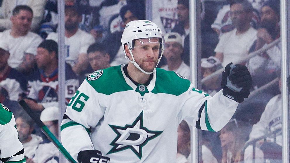 Ishockeyspelare i Dallas Stars firar mål mot motståndarlag, domare syns till vänster.