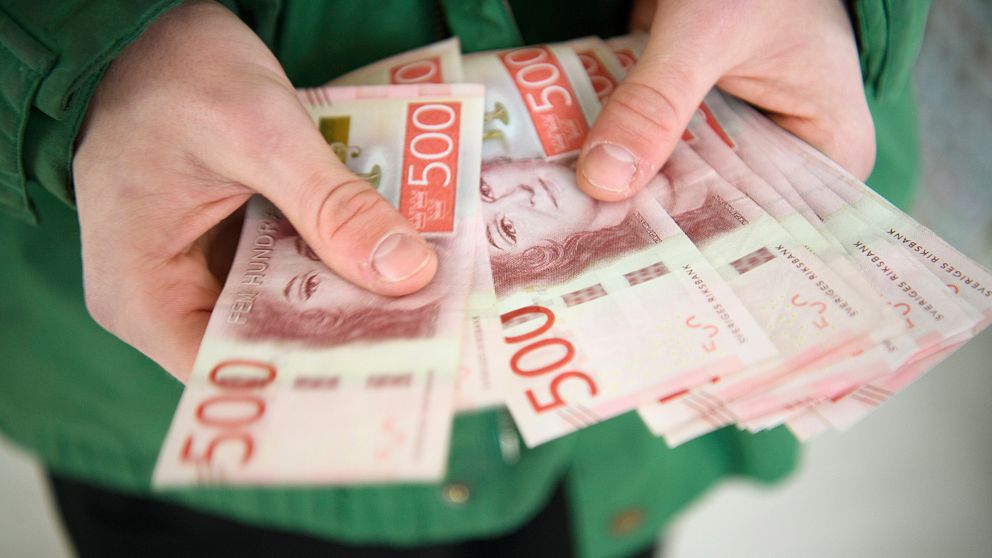 Person håller svenska femhundralappar i händerna.