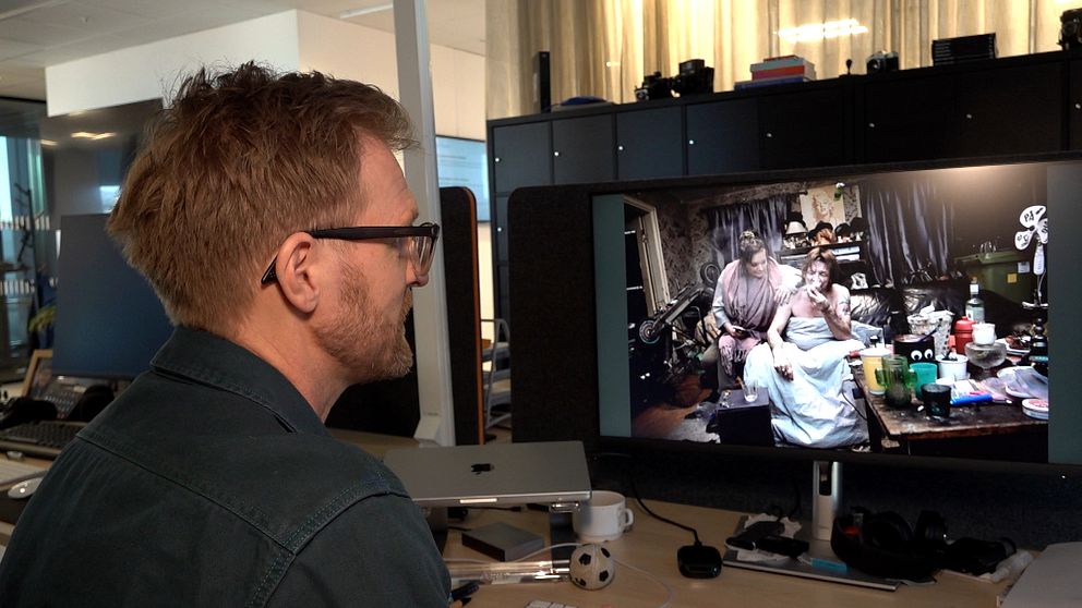 Person sitter vid skrivbord och tittar på bilder på en datorskärm.
