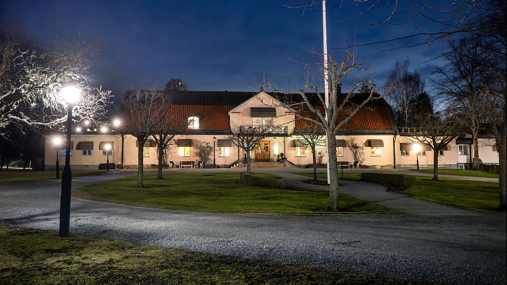 Byggnad upplyst av gatlampor under en mörk kvällshimmel.