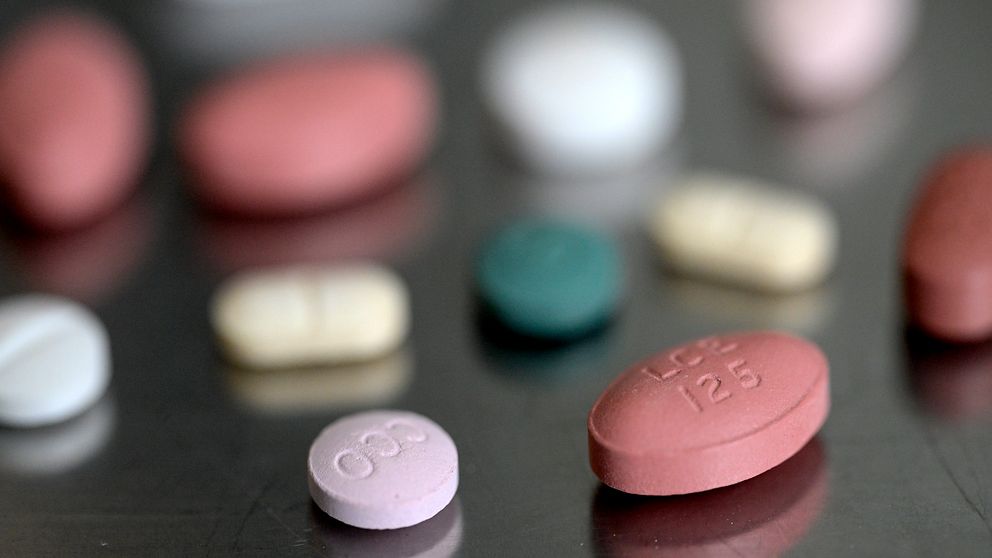 Olika typer av färgglada piller spridda på en yta, inklusive oidentifierade röda, rosa, vita och gröna tabletter.