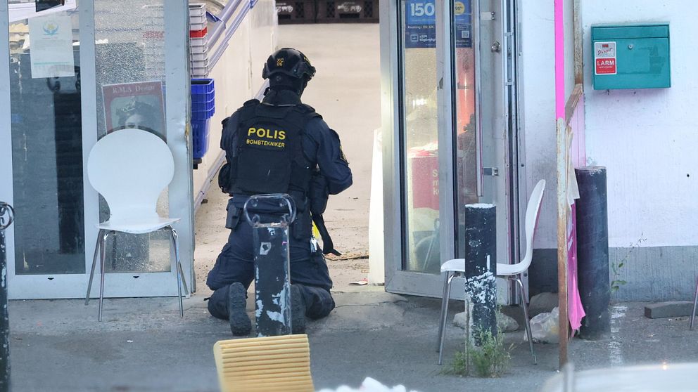 Polis på knä vid insats vid entre till mattaffär