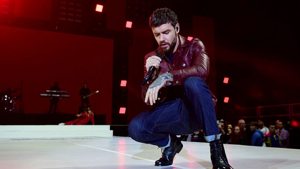 Liam Payne på en scen, hållandes en mikrofon.