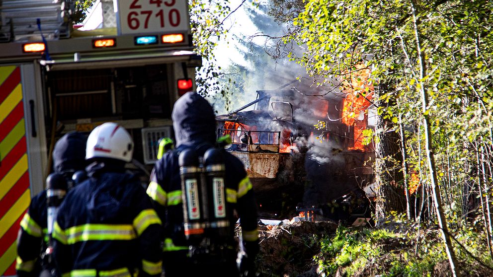 räddningstjänst släcker en båt som står på land och brinner