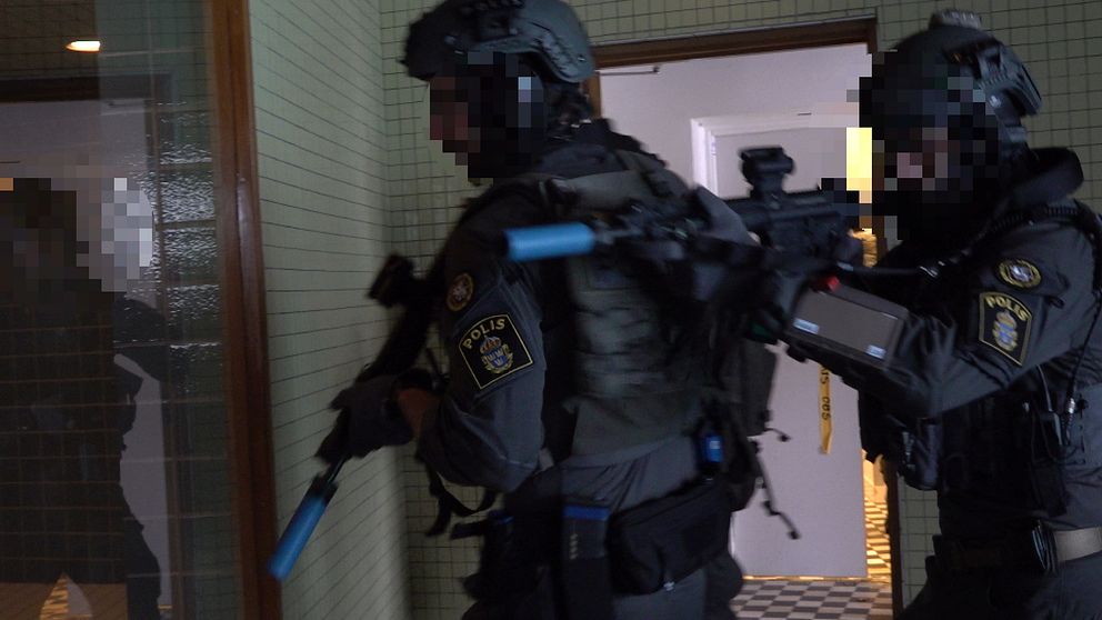 Flera poliser går in i en byggnad klädda i skyddsutrustning och utrustade med automatvapen