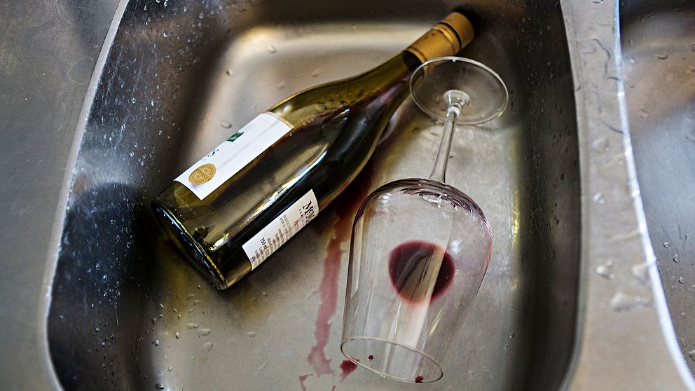 Vinflaska och vinglas med vinslatt ligger i diskho.