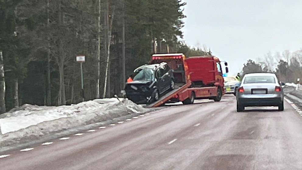 Bärgningsbil som lastar upp en svart personbil som är skadad i fram.