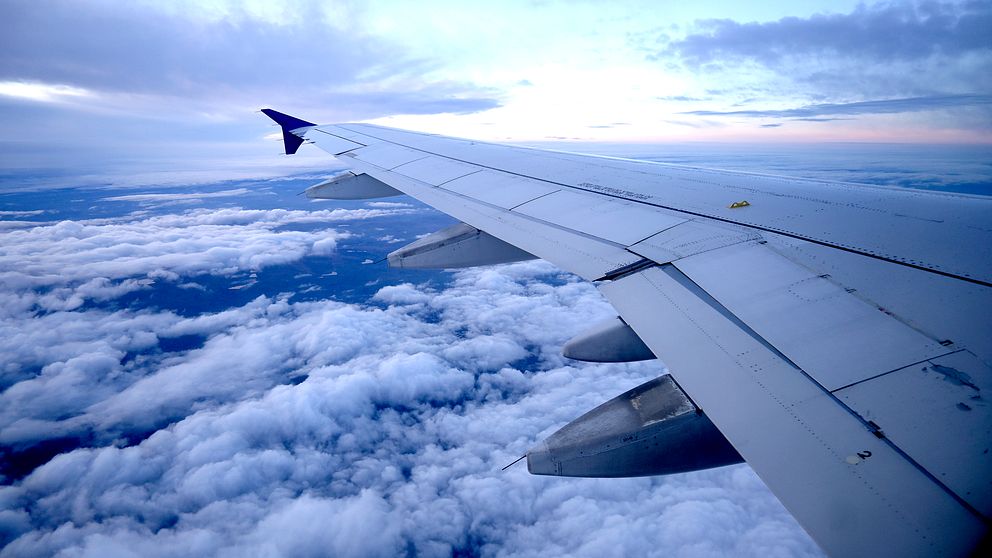 Bild tagen inifrån ett sas-flyg uppe i luften. Vänstravingen av flygplanet uppe i himlen med moln.