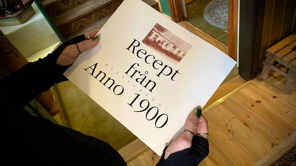 Person håller bok med texten ”Recept från Anno 1900” med recept från den gamla malmörestaurangen.