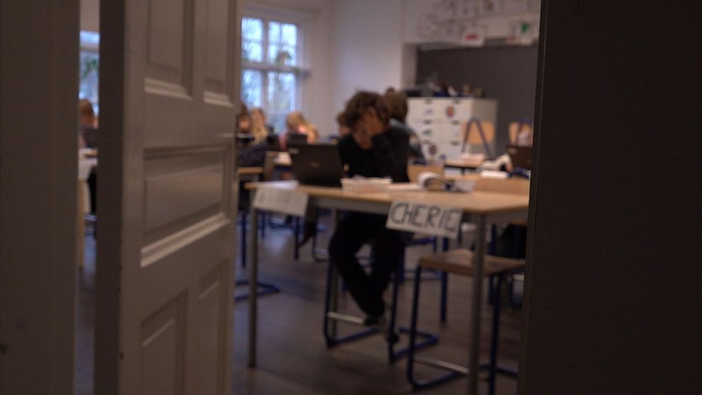 Ett klassrum där bilden är suddig, man ser elever och bänkar.
