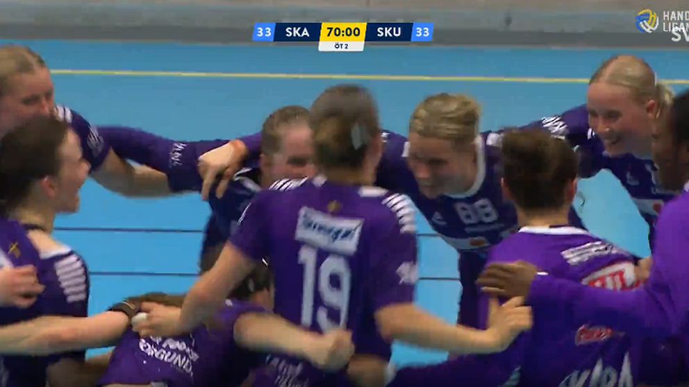 Handbollslag firar i en ring, klädda i lila tröjor på en blå spelplan. Skärmtid 79:00.