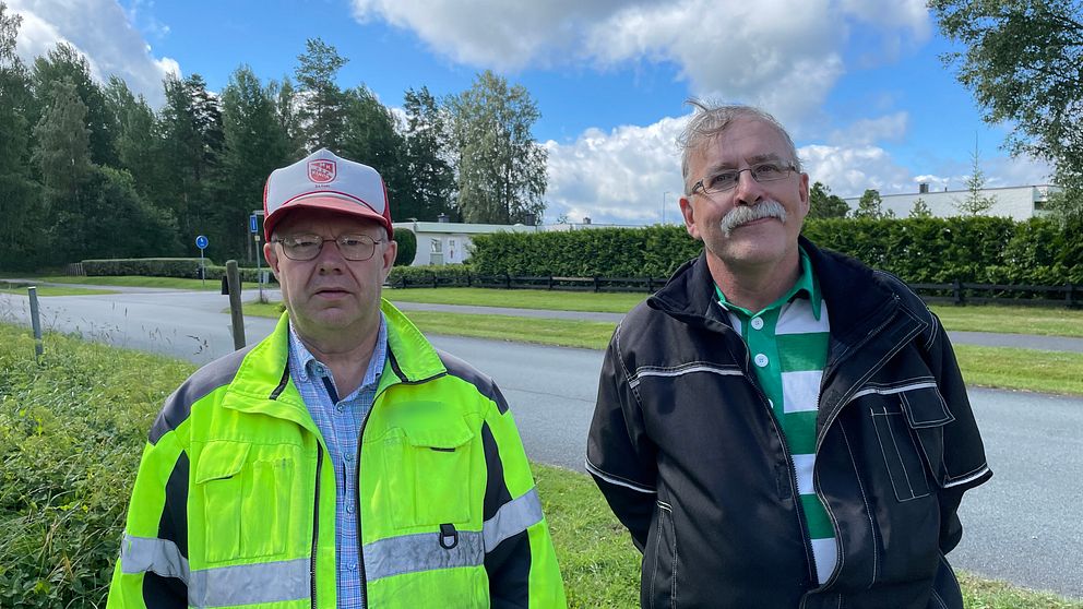 Man till vänster med reflexväst och herre till höger som ler