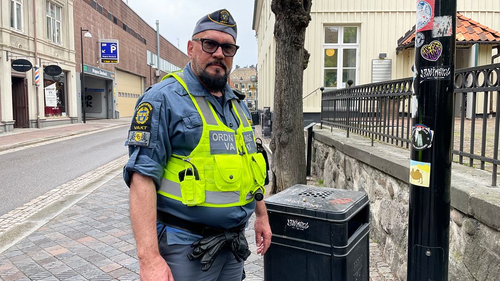 En manlig ordningsvakt står bredvid en soptunna i centrala Helsingborg.