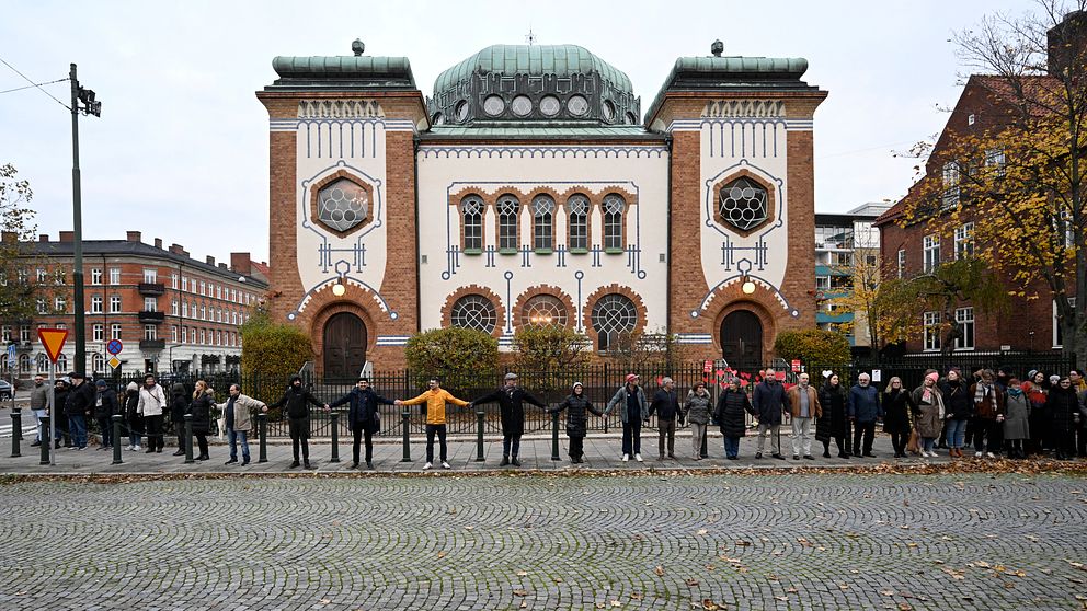 Malmöbor hand i hand bildar en ring runt synagogan i Malmö under en stödmanifestation på lördagen.