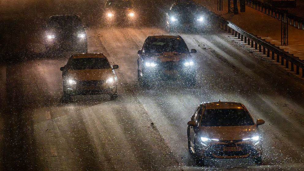 Bilar på motorväg i snöig väderlek.