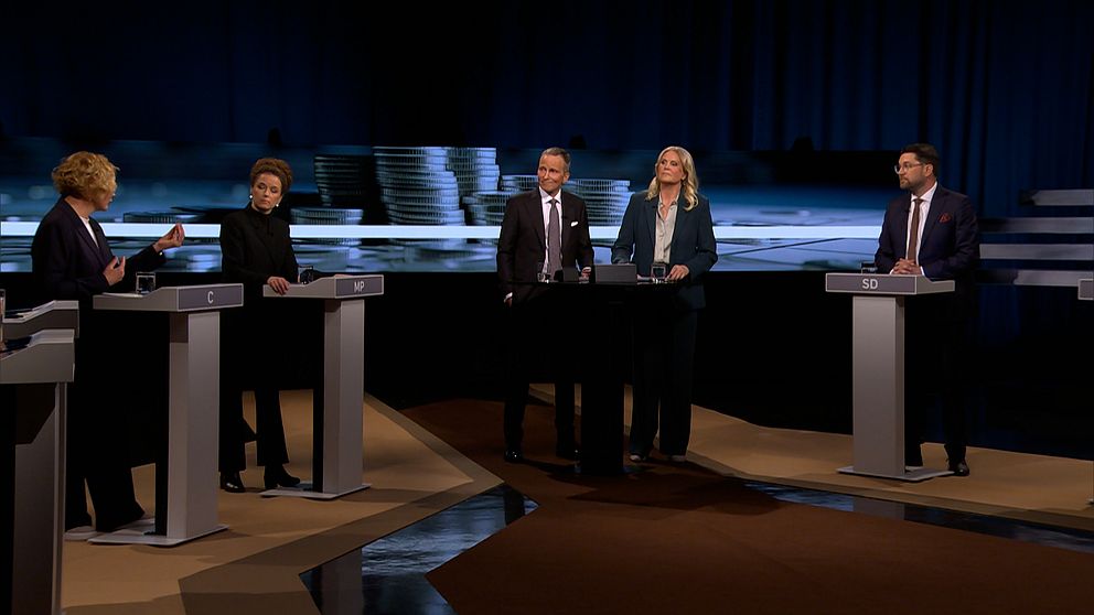 Fyra partiledare står vid talarpodium i tv-sänd politisk debatt.