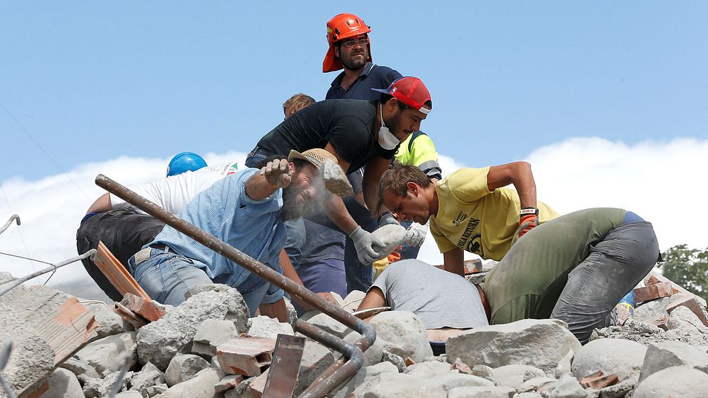 Räddningsarbetare gräver i en hög av rasmassor.