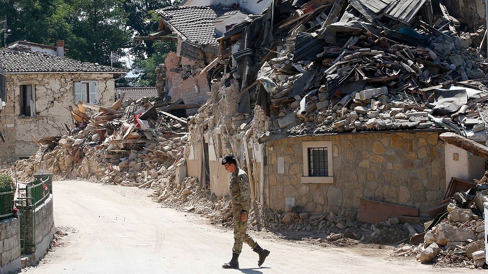 En italiensk soldat går förbi hus som står i ruiner i Villa San Lorenzo, nära byn Amatrice.