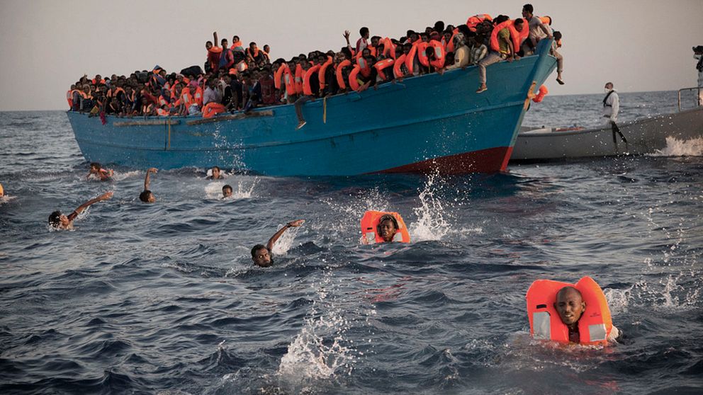 Människor i flytvästar hoppar från en båt i Medelhavet och simmar mot en räddningsbåt under måndagen.