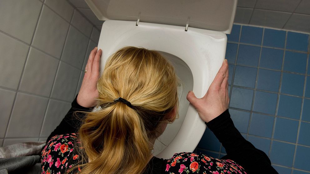 Kvinna lutad över en toalettstol.