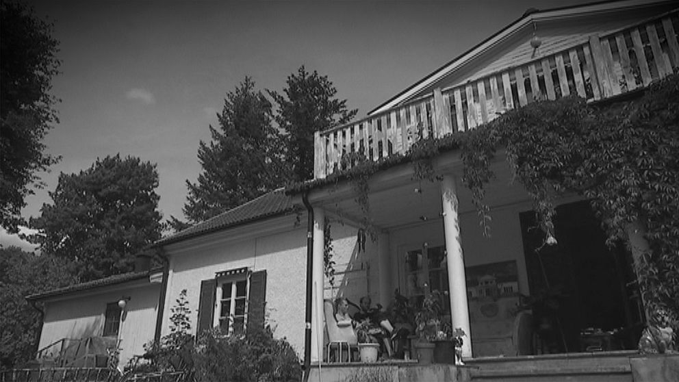 Ett vitt hus, vildvin växer på pelare på farstubron.