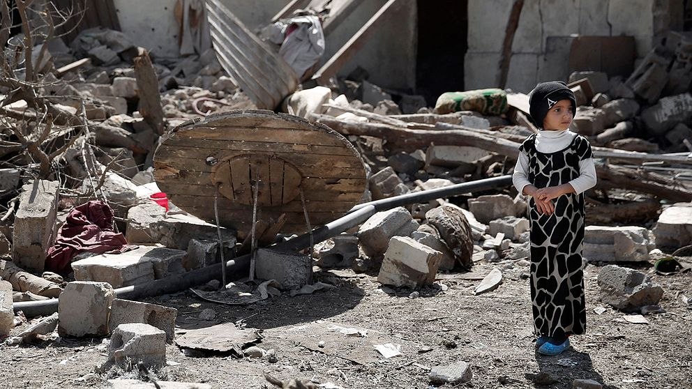 En flicka står bland resterna av ett hus efter en saudiledd flygattack i Sanaa, Jemen.