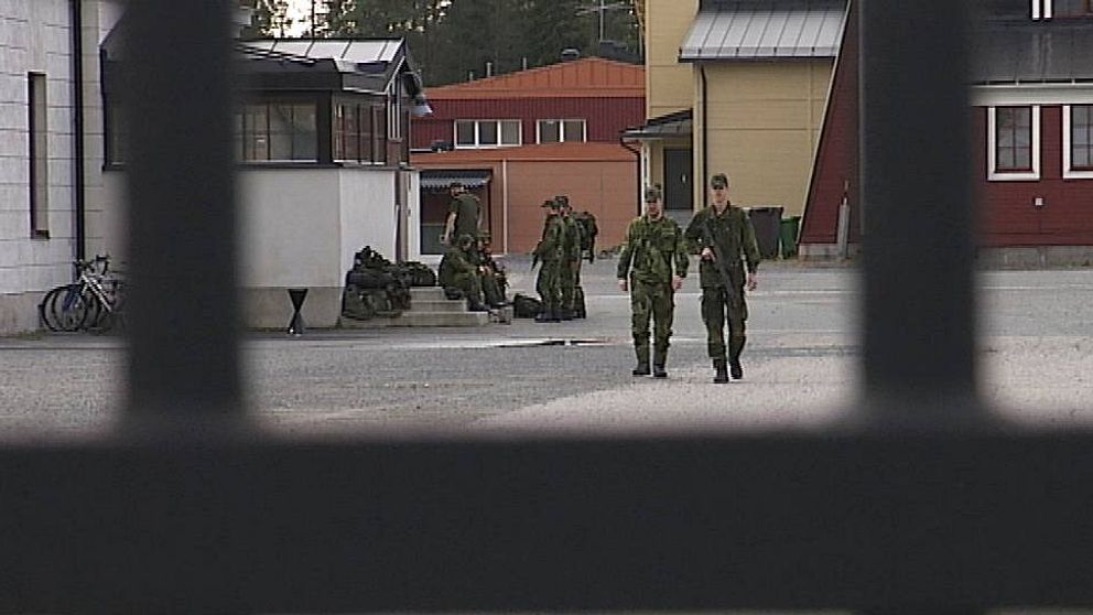 Två militärer går mot grind i förgrunden