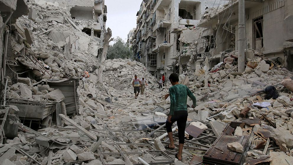 Människor går omkring i ruinerna efter bombningar i Aleppo på fredag.