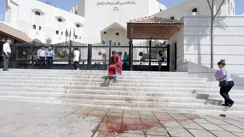 En man tvättar bortblodet efter mordet på Hahid Hattar framför för en domstol i Amman.
