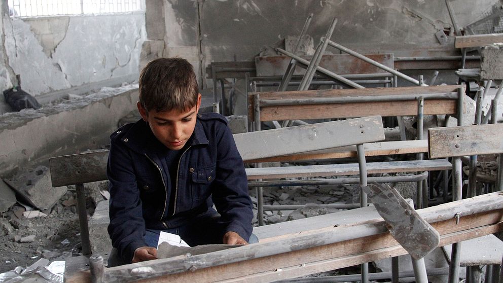 En syrisk pojke i sin sönderbombade skola i Syrien.