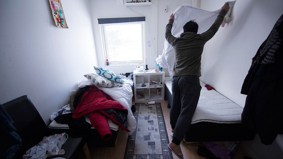 En man bäddar sin säng i ett rum på asylboende.