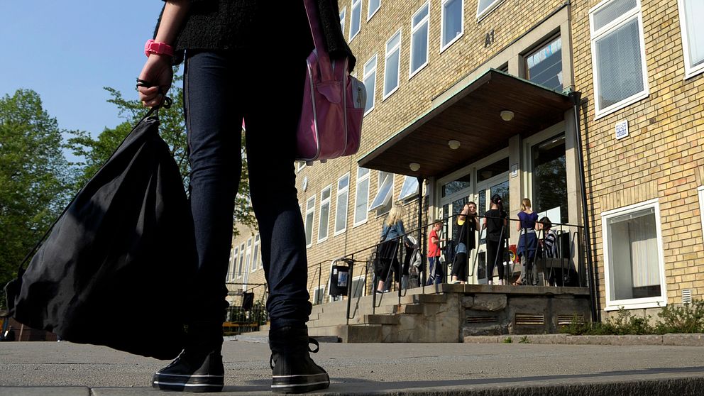 En flicka i förgrunden som står på en skolgård.