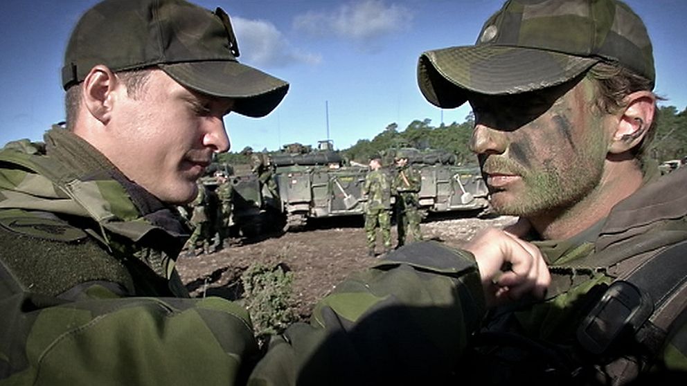 Soldater fixar krigsmask inför övning på Tofta skjutfält.
