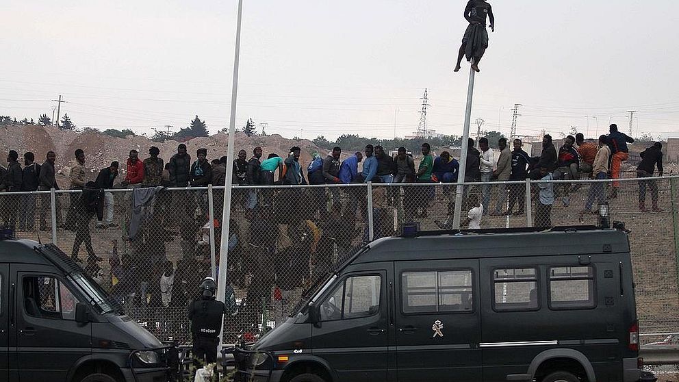 Migranter har klättrat upp på det stålstängsel som skiljer Marocko från den spanska enklaven Melilla.