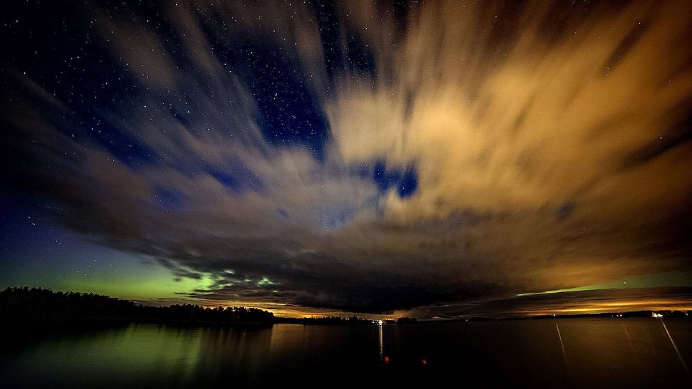 Färgsprakande norrsken på mörk himmel. Sjö.