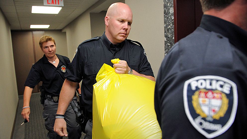En polisman bär ut paketet, som innehöll en mänsklig fot, från Kanadas konservativa partis högkvarter i Ottawa.