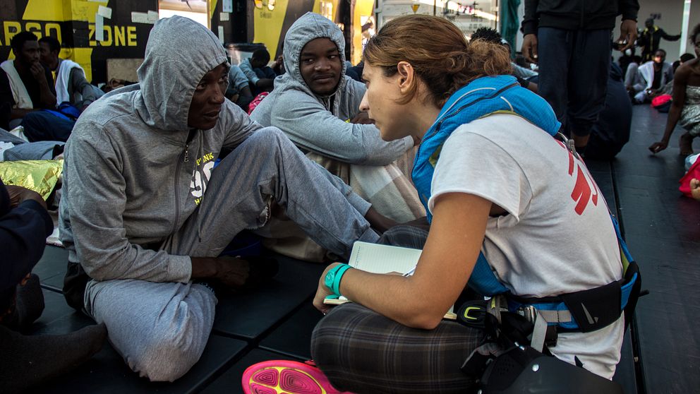 En hjälparbetare på Läkare utan gränser talar med människor som räddats ur båt.