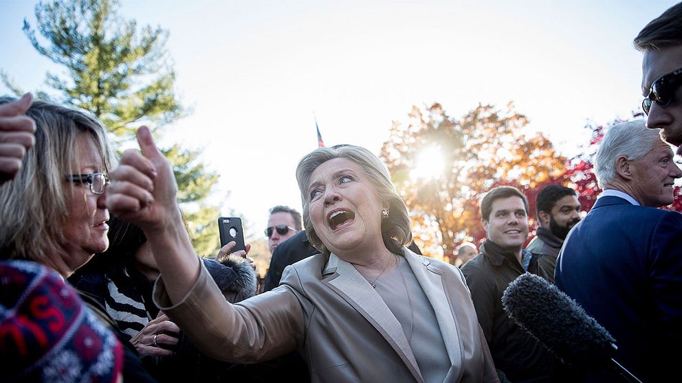 Hillary Clinton gör tummen upp till folkmassorna i samband med att hon röstar.