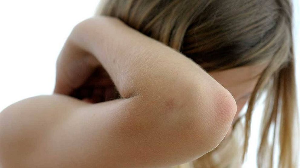 Flicka döljer ansiktet med armen, illustrerar barn som far illa.