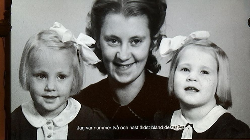 gammal, svartvit bild av en vuxen kvinna tillsammans med två barn.