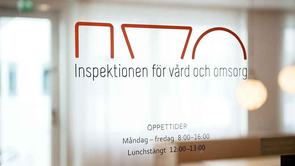 En bild på en glasdörr till inspektionen för vård och omsorg. IVOs logotyp i rött och under text om öppettider.