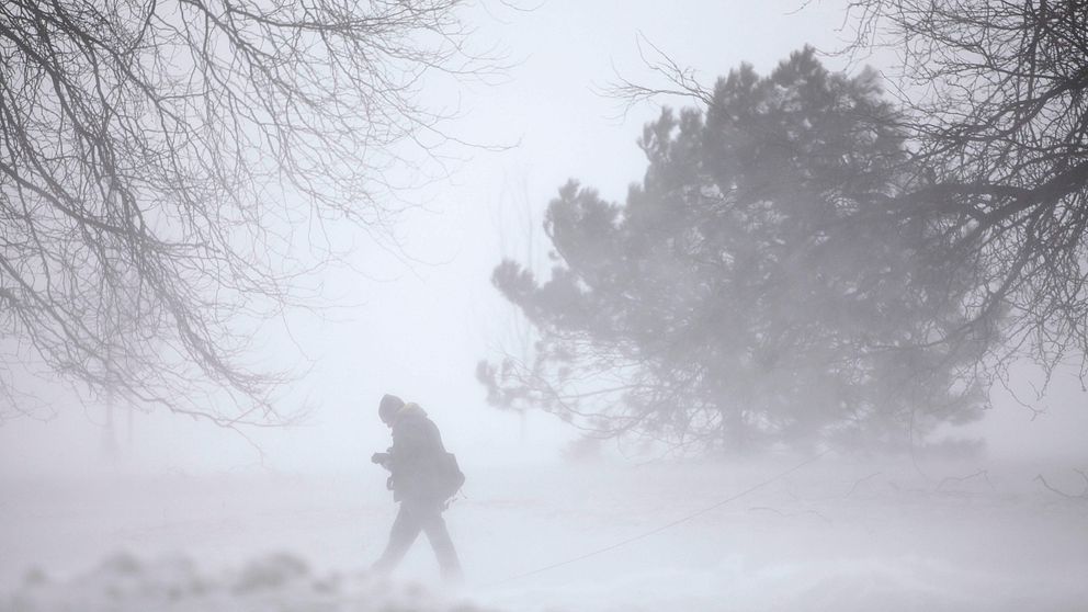 En bild på en person som går i snöstorm.