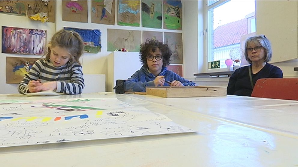 Barnakademin två barn som sitter vid ett bord med teckningar i bakgrunden