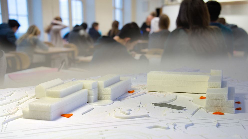 En modell av den föreslagna skolan, tillsammans med en genrebild av elever som jobbar i ett klassrum.