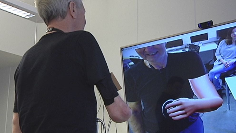 Ture Johansson står framför en skärm och skrattar åt sin animerade arm.