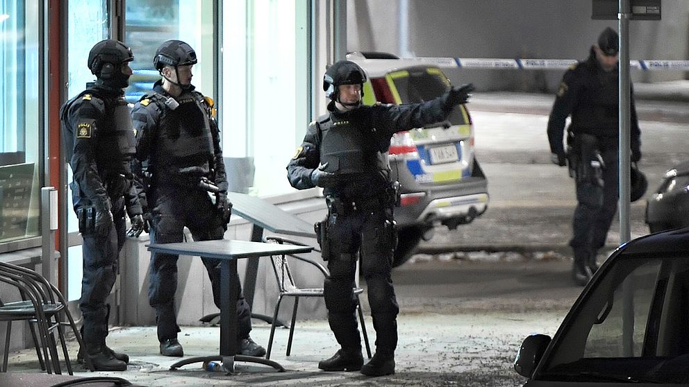 Polis utrustad med skyddsvästar och hjälmar utanför det kafé där skottlossningen ägde rum under fredagskvällen.