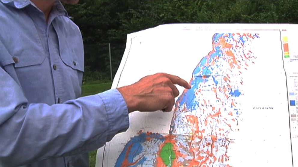Hand som pekar på karta över Öland där de olika geologiska omständigheterna är markerade med olika färger